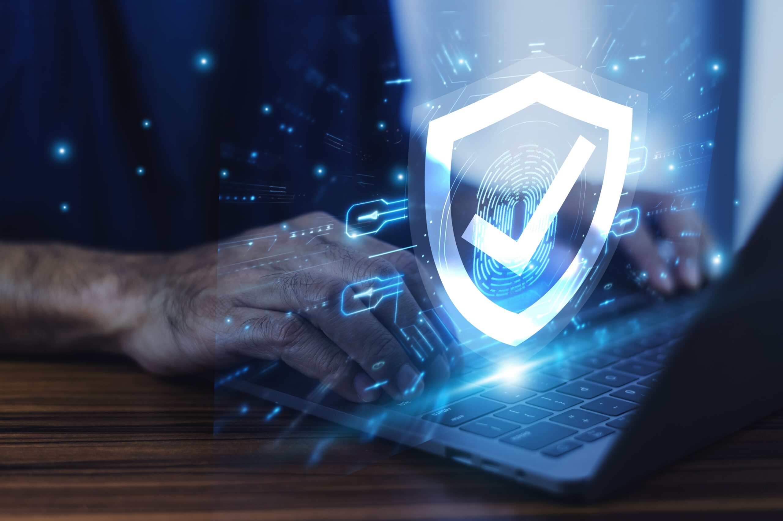 Man working on a laptop with advanced cyber security shield hovering above keyboard