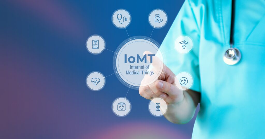 A doctor in teal scrubs interacts with a digital display labeled "IoMT Internet of Medical Things," featuring medical icons on a gradient background.
