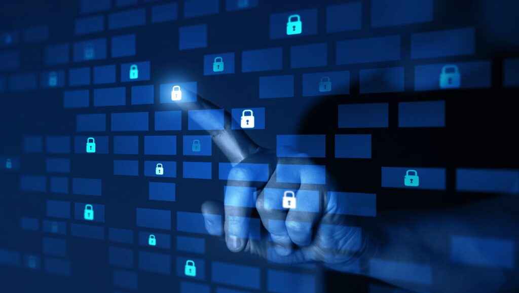 Person's hand touching a virtual screen with scattered padlocks and rectangles symbolizing cybersecurity.