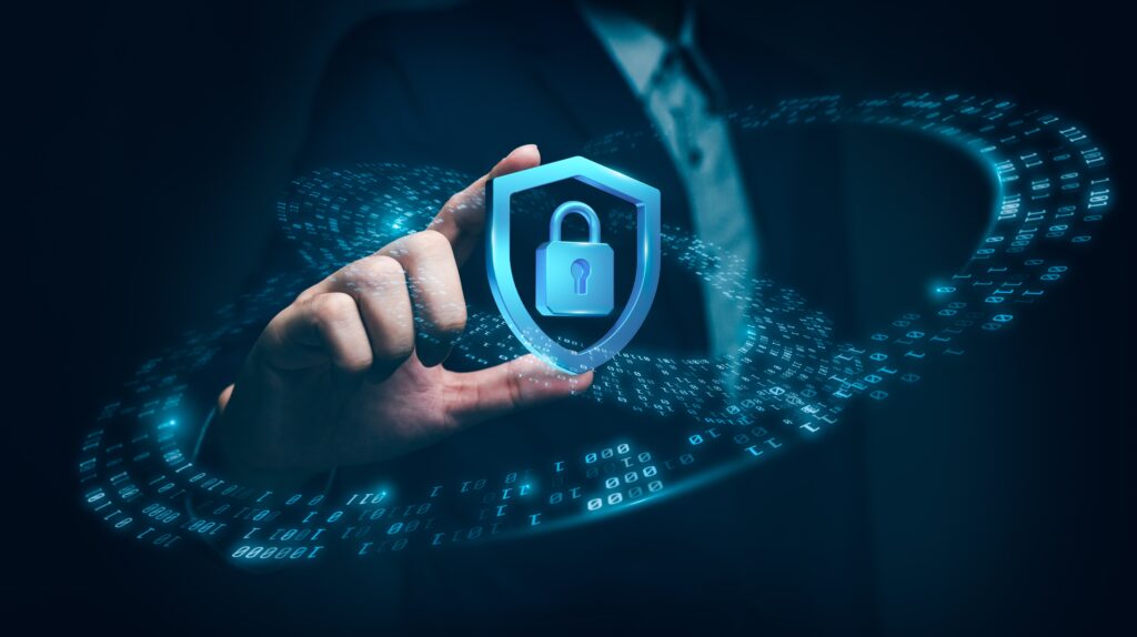 A business professional touches a glowing digital shield icon with a padlock at its center, symbolizing cybersecurity and data protection surrounded by binary code.