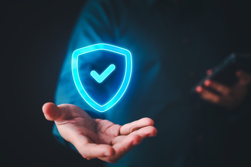  A person holds out a hand with a glowing blue shield and checkmark floating above.