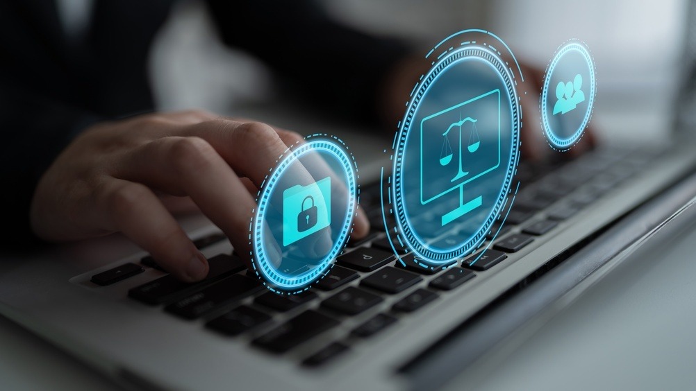 Person using a laptop with digital cybersecurity icons representing data protection, legal compliance and secure online information.